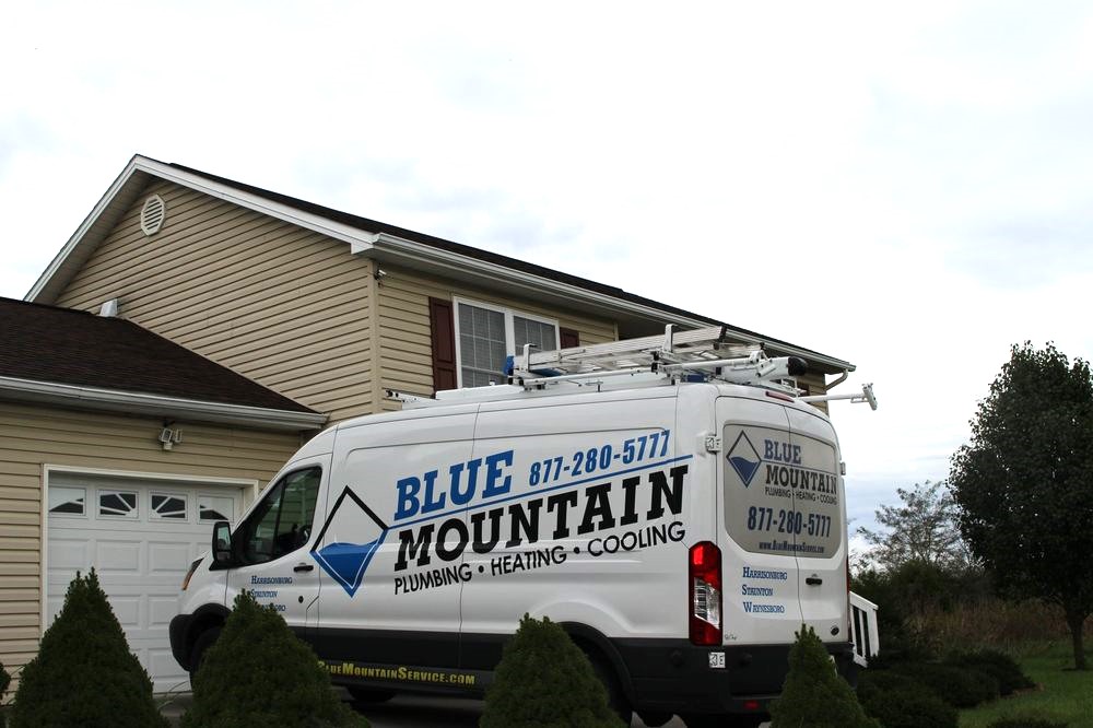 The Blue Mountain Plumbing, Heating, and Cooling van parked outside a home