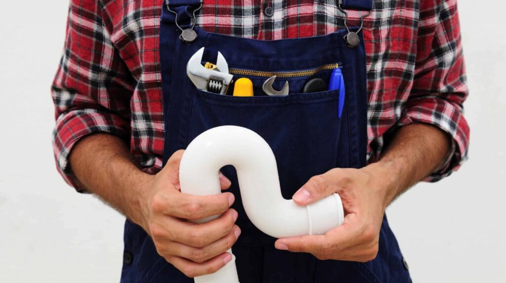 A plumbing technician is holding a PVC pipe.